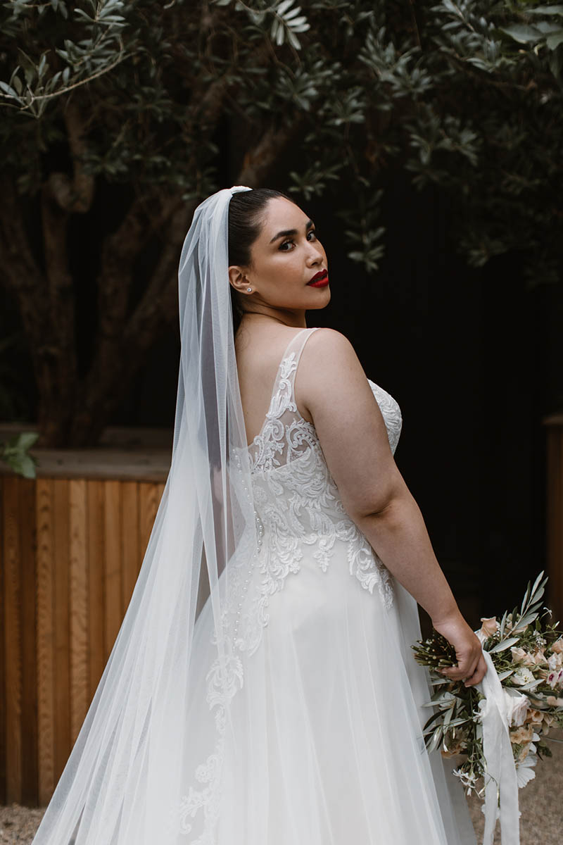 Three things we love on our Robyn wedding dress: embroidered lace, curve-hugging silhouette, & the train. It's everything a plus-size ball gown should be